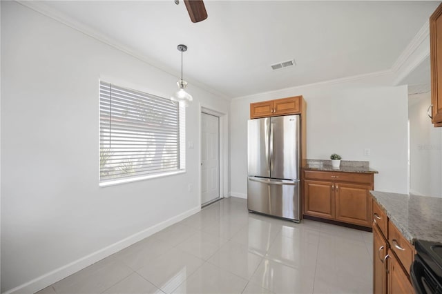 kitchen with visible vents, light stone counters, brown cabinetry, and freestanding refrigerator