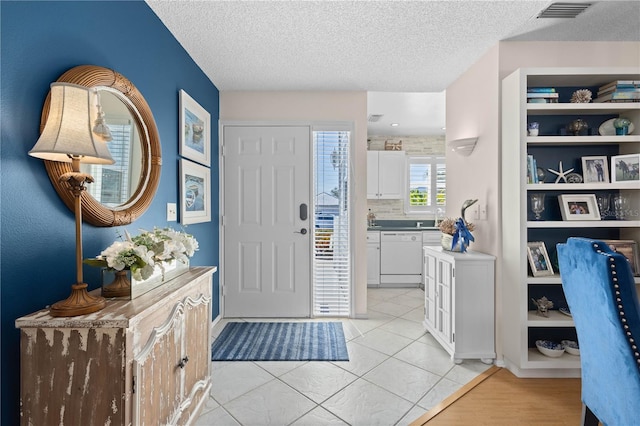 entrance foyer featuring visible vents, a textured ceiling, and light tile patterned floors