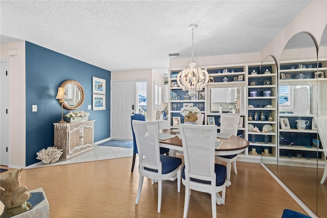 dining room with a chandelier, visible vents, a textured ceiling, and wood finished floors