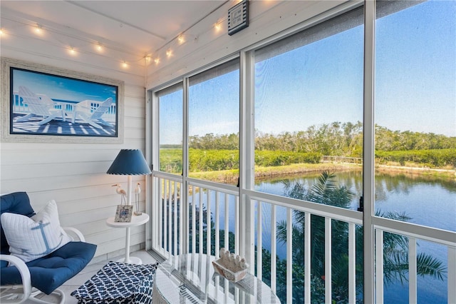 sunroom / solarium with rail lighting and a water view