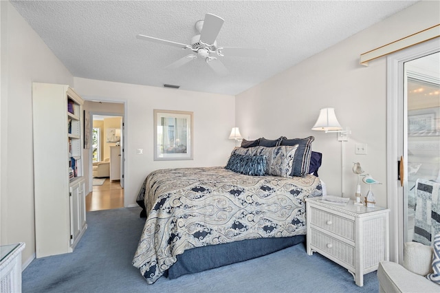 carpeted bedroom with a textured ceiling, visible vents, and a ceiling fan