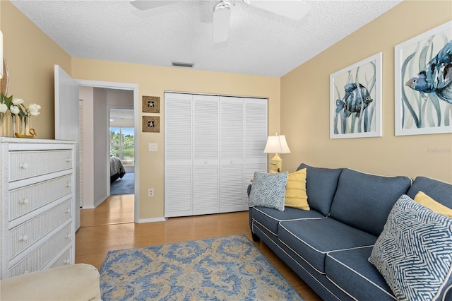 living area featuring a textured ceiling, visible vents, and wood finished floors