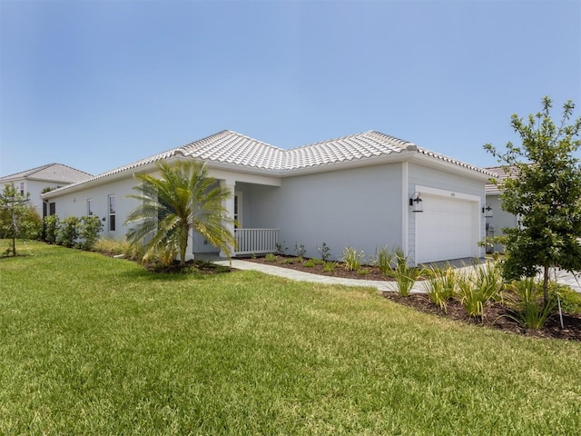 view of front of home featuring a garage, a tiled roof, a front lawn, and stucco siding