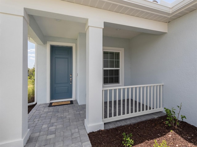 doorway to property with covered porch and stucco siding