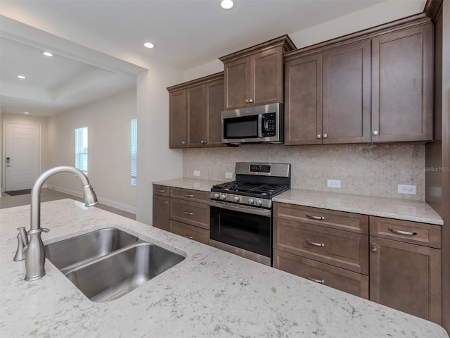 kitchen featuring light stone counters, recessed lighting, backsplash, appliances with stainless steel finishes, and a sink