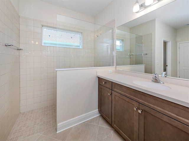 bathroom with tile patterned flooring, vanity, baseboards, and a walk in shower