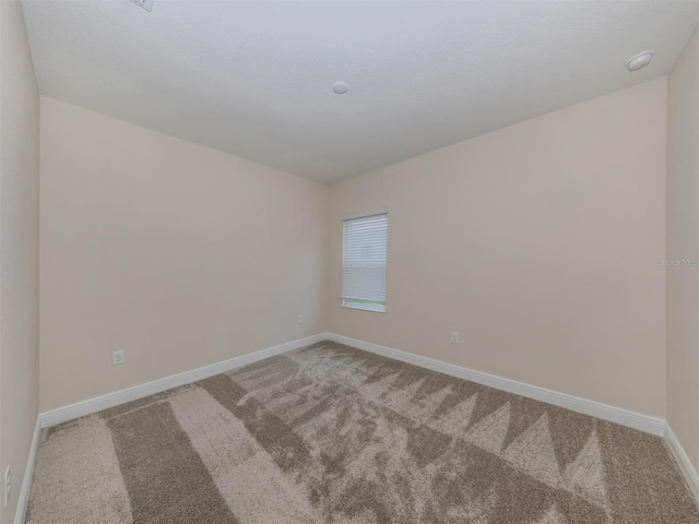 spare room featuring carpet floors and baseboards