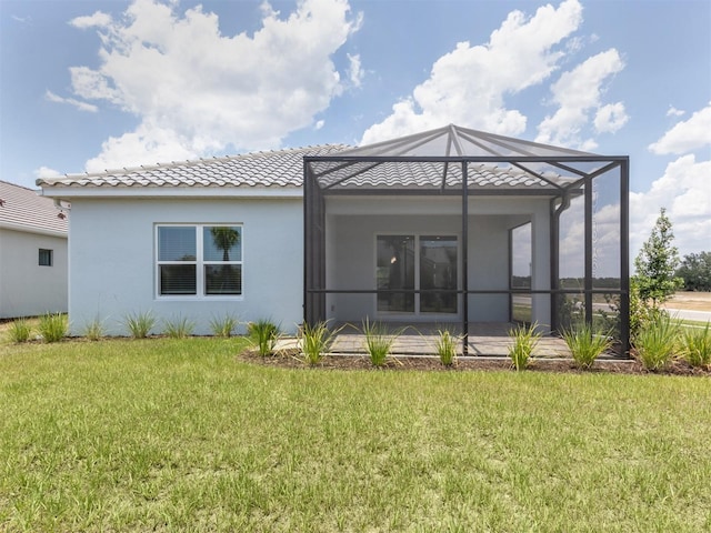 back of property with a yard, a lanai, a tiled roof, and stucco siding