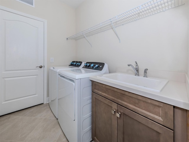 washroom with cabinet space, visible vents, washing machine and clothes dryer, a sink, and light tile patterned flooring