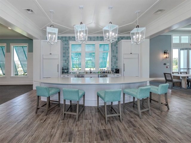 kitchen with built in refrigerator, wood tiled floor, white cabinetry, and paneled refrigerator