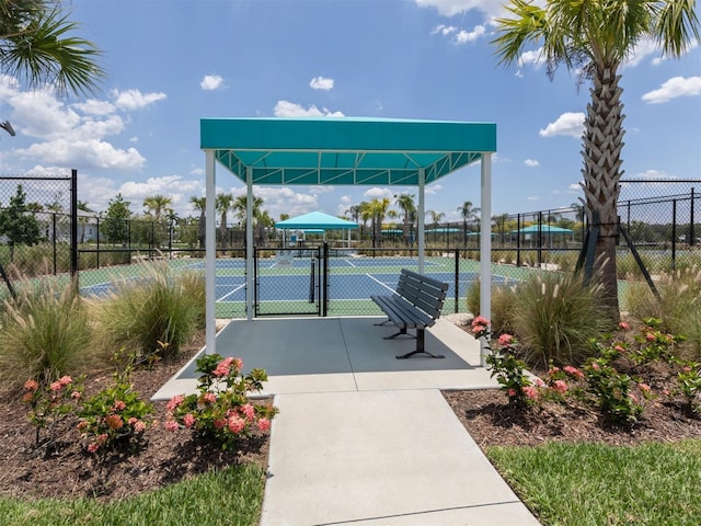 surrounding community with a tennis court, fence, and a gate