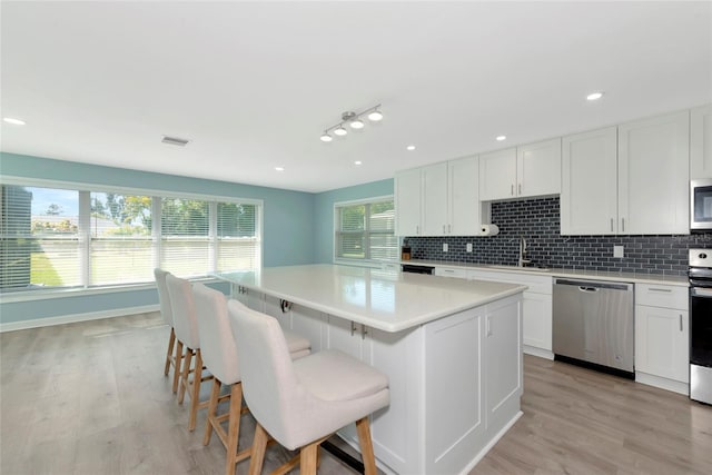 kitchen with appliances with stainless steel finishes, visible vents, a sink, and backsplash