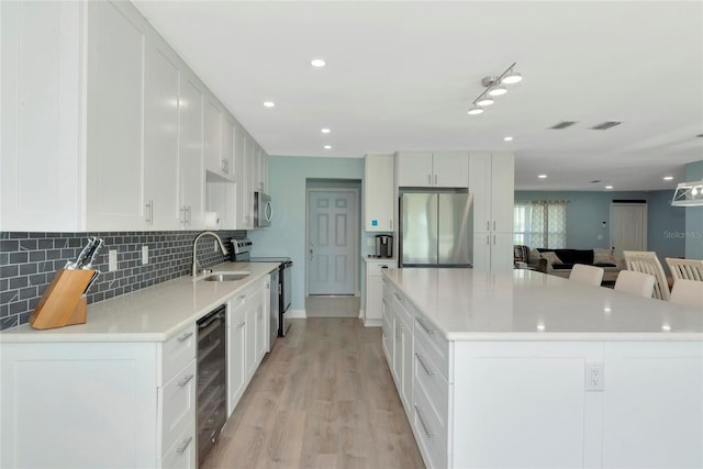 kitchen with wine cooler, stainless steel appliances, a spacious island, a sink, and backsplash