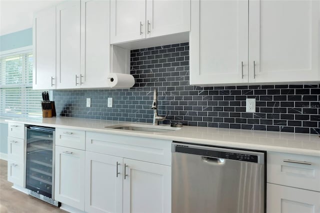 kitchen featuring beverage cooler, a sink, white cabinets, stainless steel dishwasher, and decorative backsplash