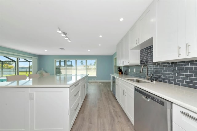 kitchen featuring dishwasher, tasteful backsplash, a sink, and a healthy amount of sunlight