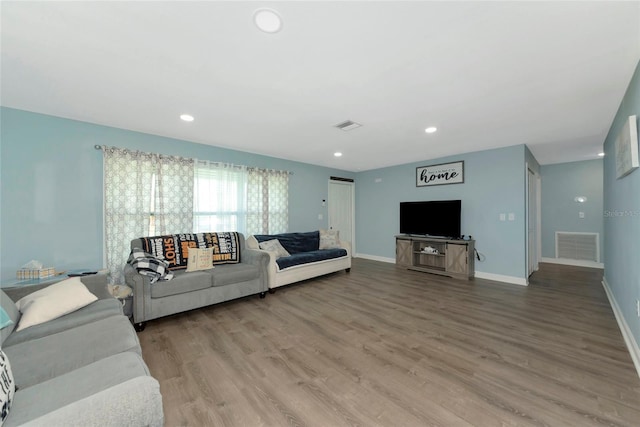 living area featuring baseboards, visible vents, and wood finished floors