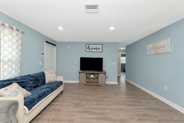 living room featuring recessed lighting, baseboards, visible vents, and light wood finished floors