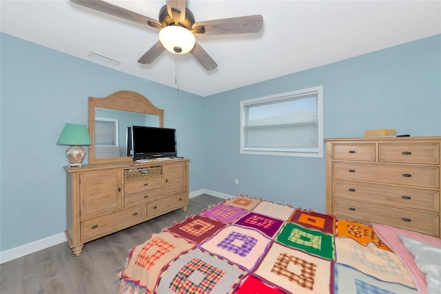 bedroom with a ceiling fan, wood finished floors, visible vents, and baseboards