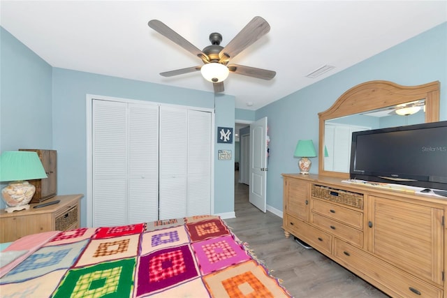 bedroom featuring visible vents, baseboards, a ceiling fan, light wood-style floors, and a closet