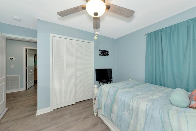 bedroom with wood finished floors, a ceiling fan, visible vents, baseboards, and a closet