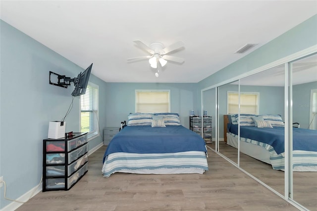 bedroom with a closet, wood finished floors, visible vents, and baseboards