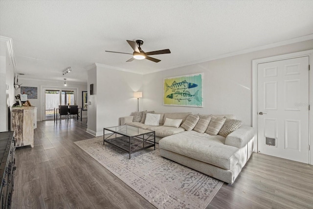 living room with ceiling fan, a textured ceiling, ornamental molding, and dark wood-style flooring