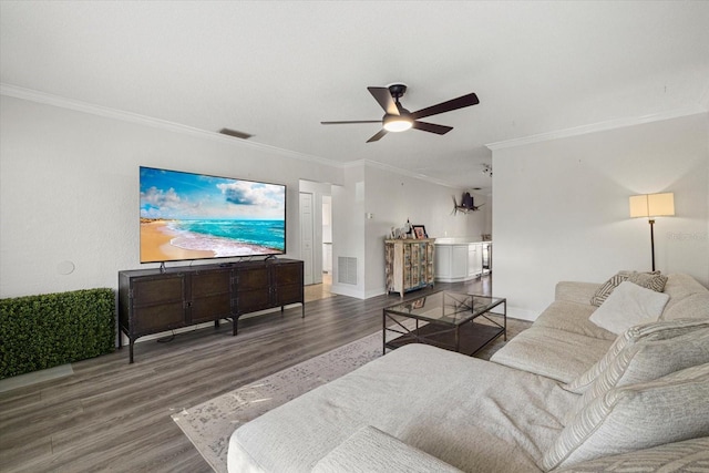 living area with ornamental molding, wood finished floors, visible vents, and a ceiling fan