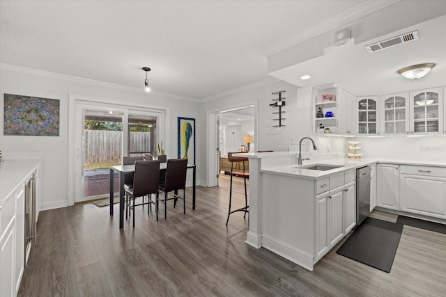 kitchen with visible vents, a sink, a peninsula, and white cabinetry