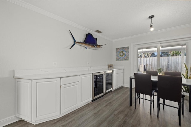 bar with beverage cooler, visible vents, and crown molding