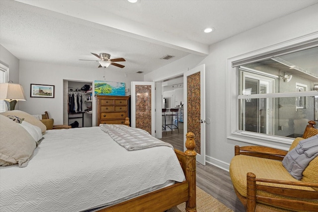 bedroom with a textured ceiling, ceiling fan, wood finished floors, a spacious closet, and a closet