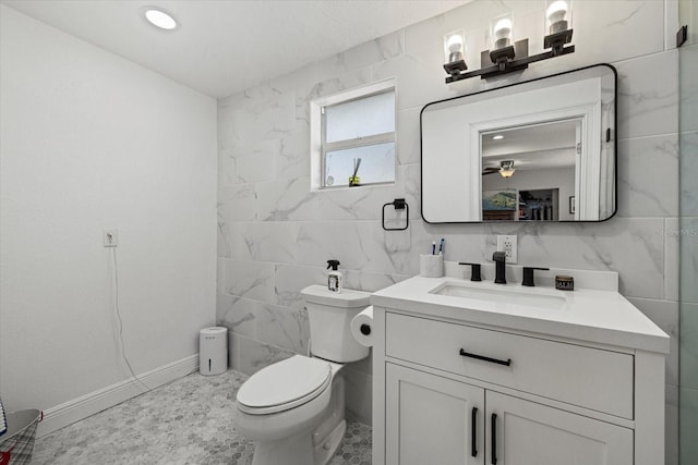 bathroom with toilet, vanity, and tile walls