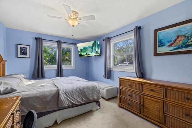 bedroom featuring a textured ceiling, a ceiling fan, and light colored carpet