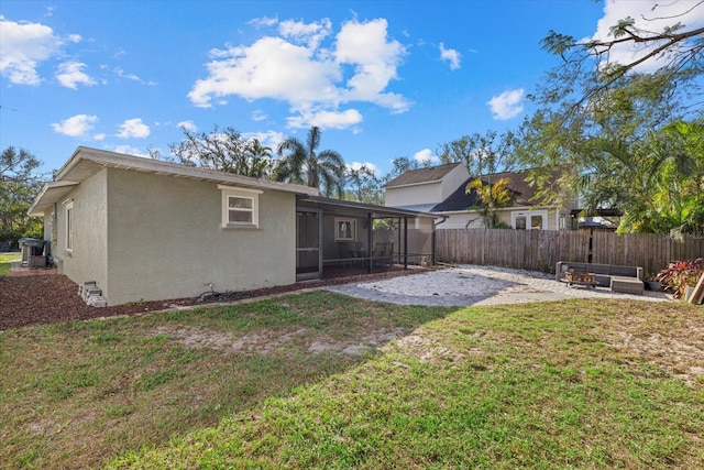 back of property with a lawn, a sunroom, fence, a patio area, and stucco siding