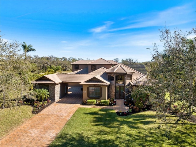 view of front of property featuring a tiled roof, a front lawn, decorative driveway, and stucco siding