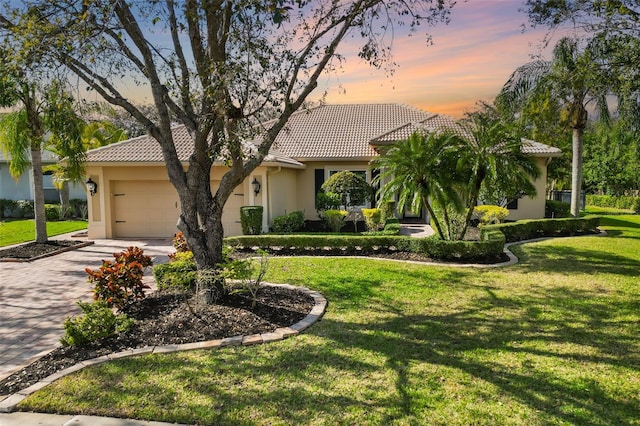 view of front of home featuring a tile roof, stucco siding, concrete driveway, an attached garage, and a front lawn