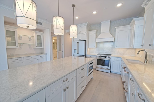 kitchen featuring visible vents, high end stainless steel range, premium range hood, white fridge with ice dispenser, and a sink