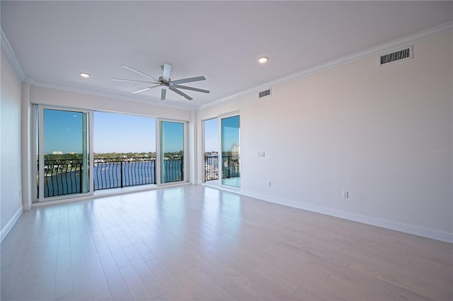 empty room featuring baseboards, visible vents, ornamental molding, and wood finished floors