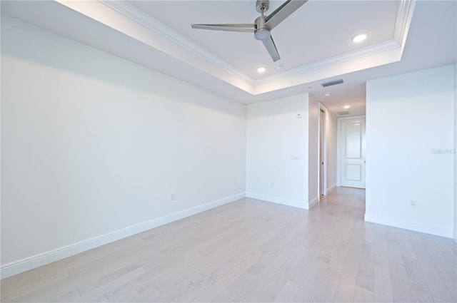 spare room featuring ornamental molding, a raised ceiling, visible vents, and light wood-style floors