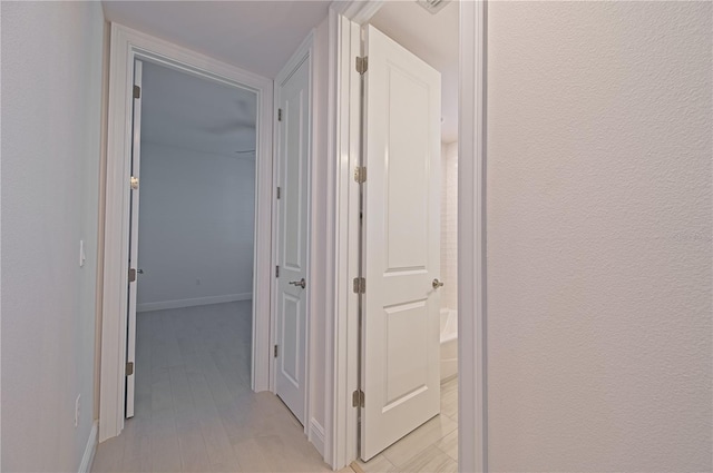 hall with light wood finished floors and baseboards