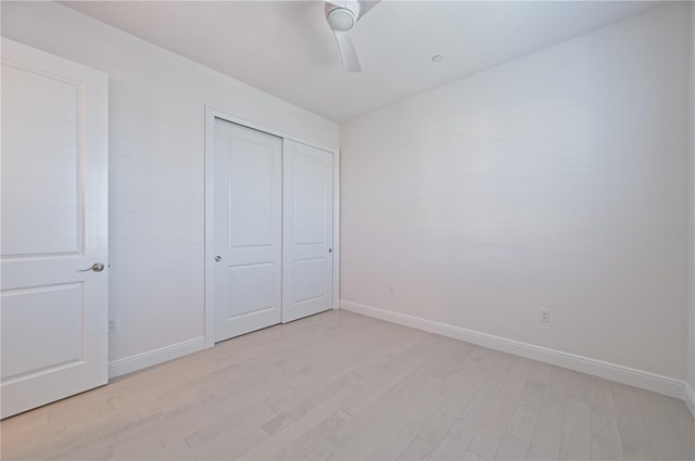 unfurnished bedroom featuring ceiling fan, a closet, light wood-type flooring, and baseboards