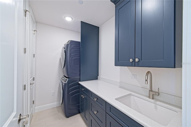 laundry area with stacked washing maching and dryer, a sink, cabinet space, and baseboards