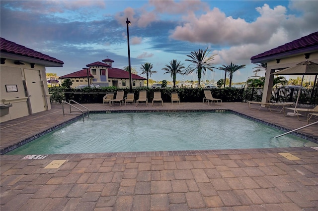 pool at dusk with a community pool, fence, and a patio