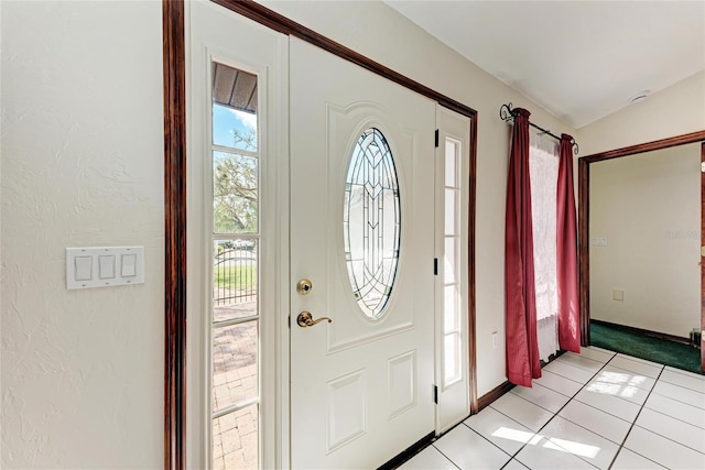 entryway featuring baseboards, vaulted ceiling, and light tile patterned flooring