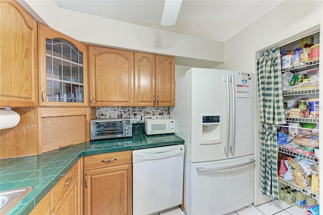 kitchen featuring a toaster, tile countertops, decorative backsplash, glass insert cabinets, and white appliances