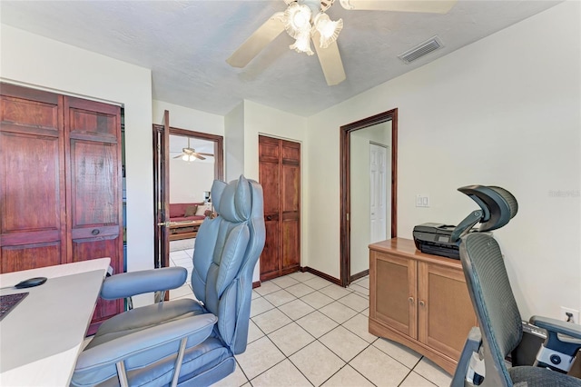 office space with a ceiling fan, visible vents, baseboards, and light tile patterned flooring