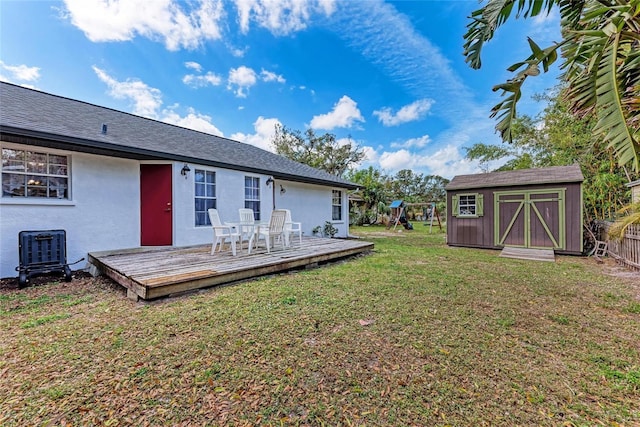 rear view of house featuring a deck, cooling unit, an outdoor structure, a lawn, and a shed