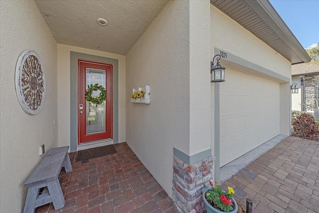 property entrance featuring a garage and stucco siding