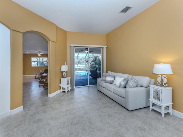 living area featuring arched walkways, visible vents, a ceiling fan, a sunroom, and baseboards