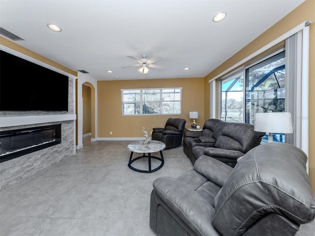 living room featuring recessed lighting, visible vents, arched walkways, and a stone fireplace