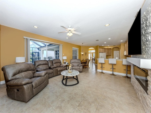 living room with recessed lighting, ceiling fan, arched walkways, and baseboards